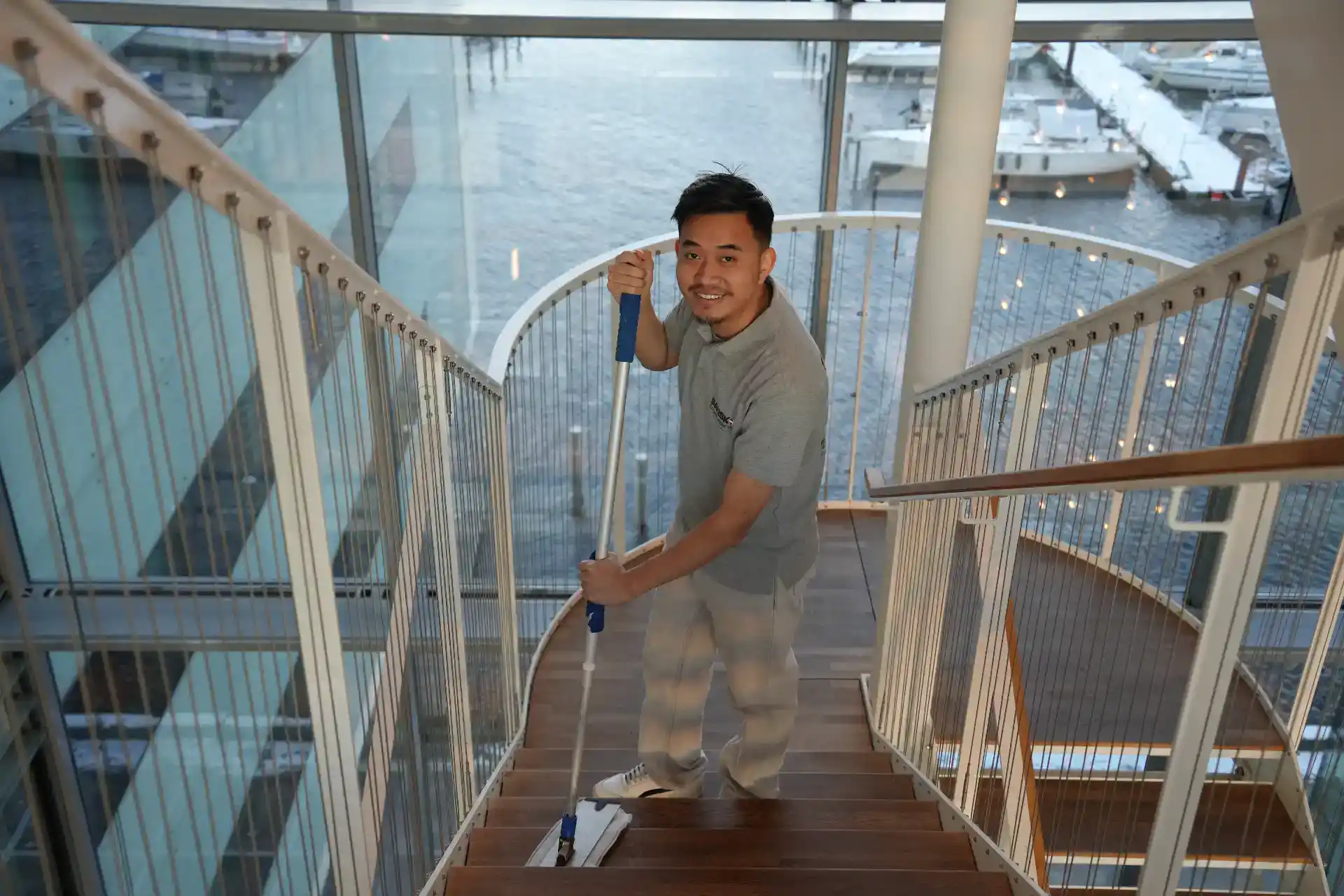 Rengøringsmedarbejder på trappen i en kontorbygning med udsigt over havnen.