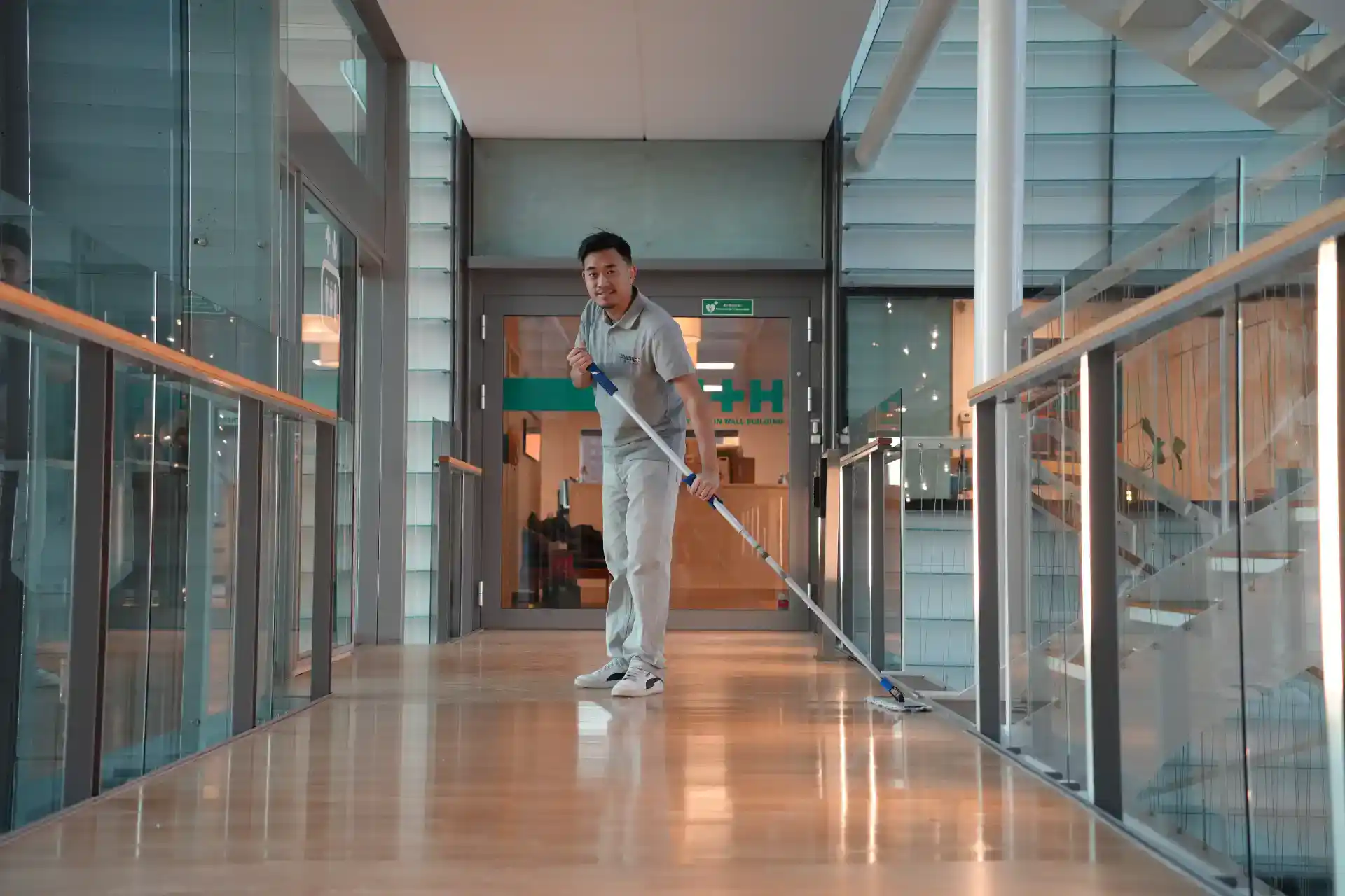 Mand rengør gulv i moderne erhvervsbygning med moppe.