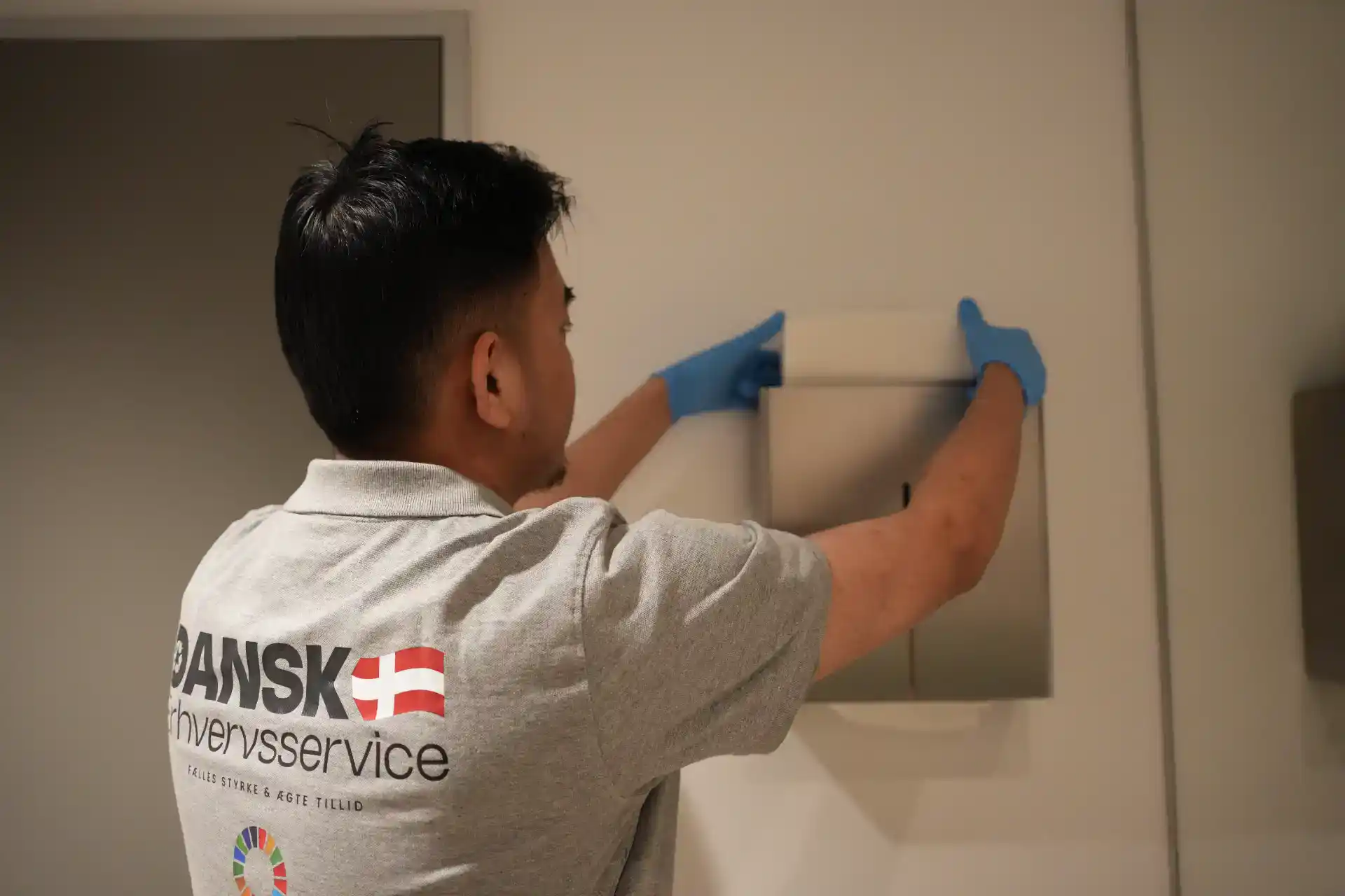 Håndværker i arbejdstøj monterer elektrisk udstyr på væggen.