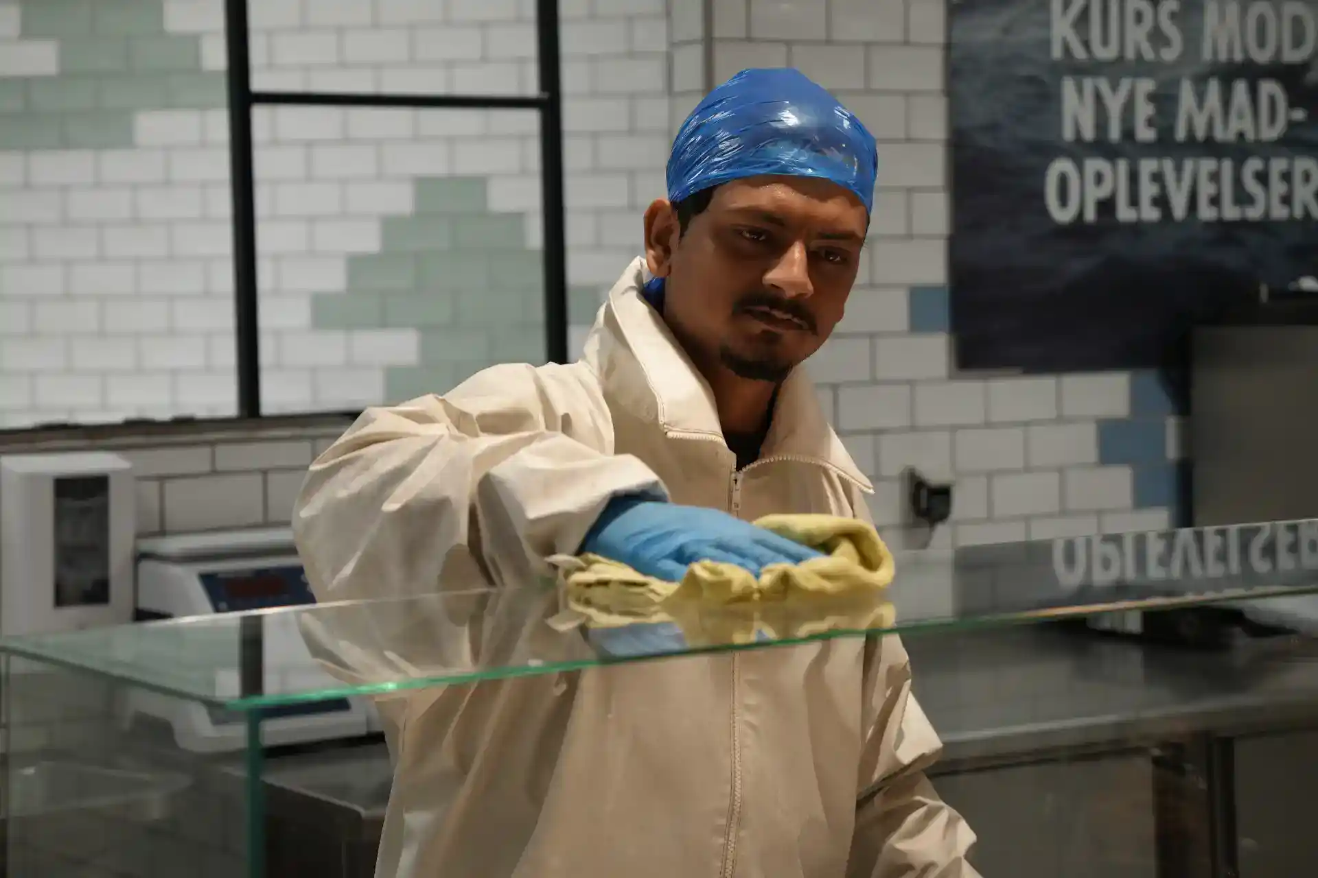 Mand i rengøringsudstyr rengør glas i et erhvervsområde.