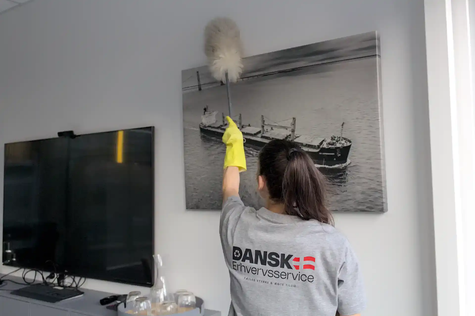 Rengøring af vægkunst med mikrofiberklud af en medarbejder i Dansk Erhvervsservice.