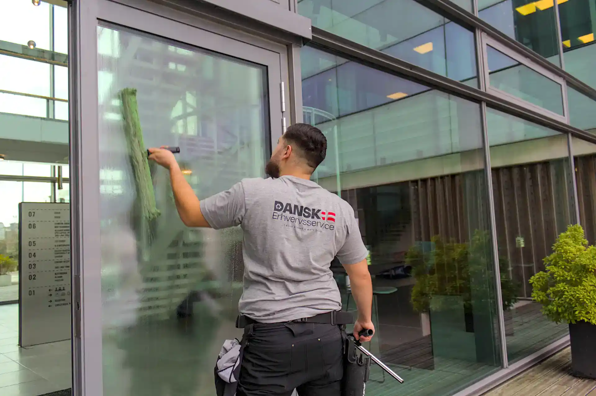 Vinduespudser rengør store glasfacader på kontorbygning.