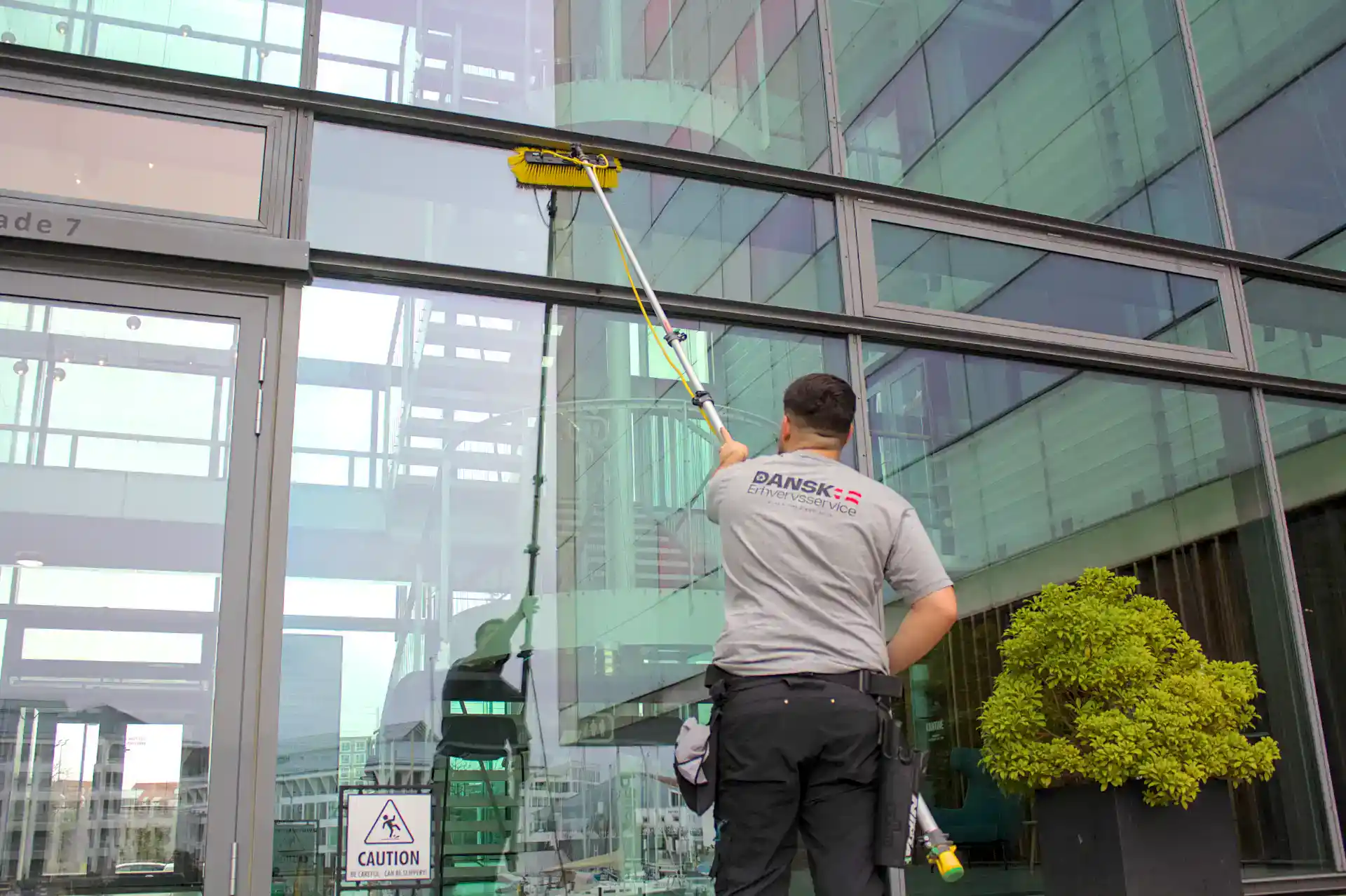 Professionel vinduespudsning af stor erhvervsbygning med skinnende ruder.
